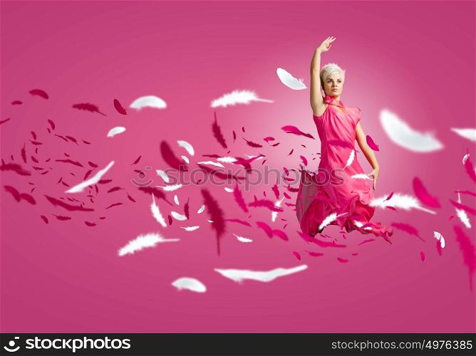 Carefree woman. Young attractive woman in pink dress jumping high
