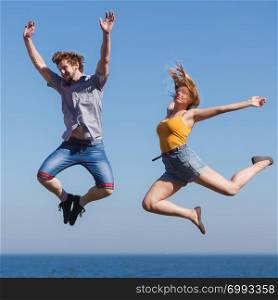 Carefree young couple friends jumping by sea ocean water. Happy woman and man having fun. Summer happiness and freedom.. Carefree couple jumping by sea ocean water.