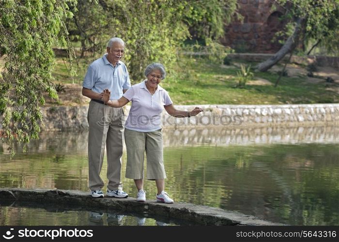 Careful mature woman balancing while walking with man in park