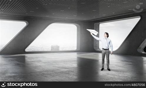 Careless businessman in office. Young businessman in modern interior playing with paper plane