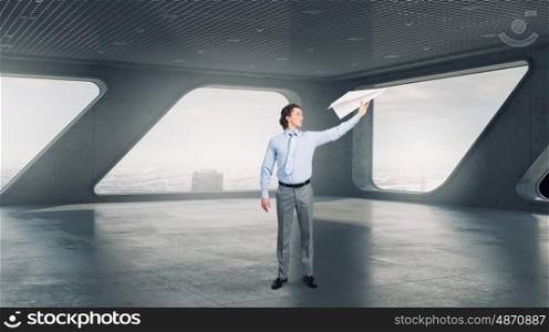 Careless businessman in office. Young businessman in modern interior playing with paper plane