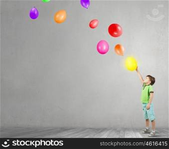Careless happy child. Little cute boy playing joyfully with colorful balloon
