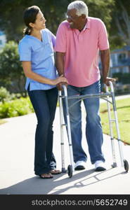 Carer Helping Senior Man With Walking Frame