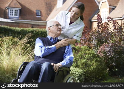 Carer Pushing Senior Man In Wheelchair