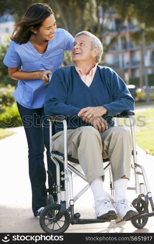 Carer Pushing Senior Man In Wheelchair