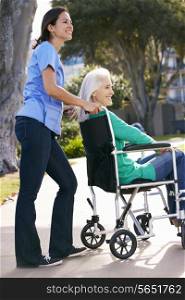 Carer Pushing Senior Woman In Wheelchair