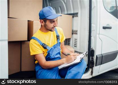 Cargo delivery service, male courier in uniform and truck with cardboard boxes.Empty container. Cargo delivery, courier and truck with boxes