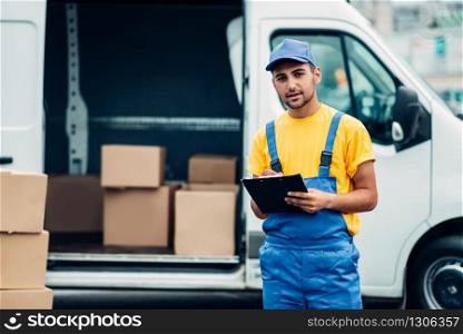 Cargo delivery service, male courier in uniform with box in hand unloads truck with cardboard parcels. Empty container. Cargo delivery service, male courier unload truck