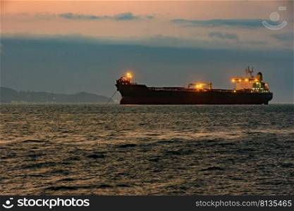 Cargo ship anchored in the waters of Ilhabela Island at dusk with the mountains in the background. Big cargo ship anchored in the waters of Ilhabela Island at sunset