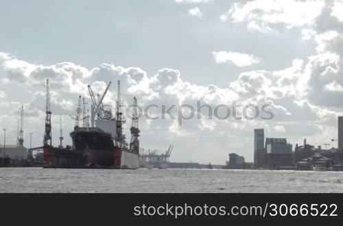 Cargo ship in Hamburg port. Bright backlit clouds.
