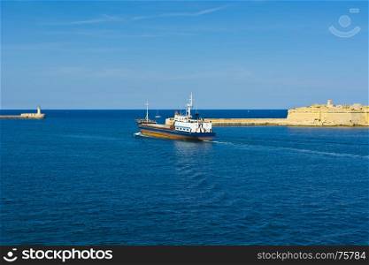 Cargo ship leaves the harbor of Valletta. Lighthouses indicate the entrance to the ports of Malta