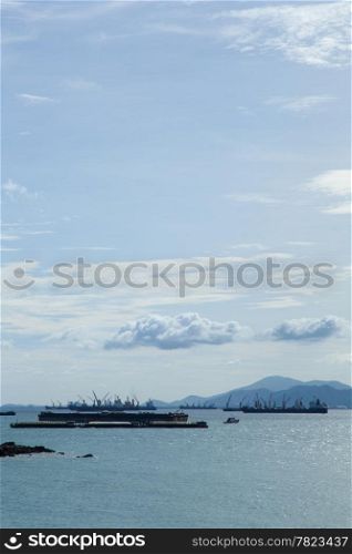 cargo ship Moored offshore. Behind the mountains and the sky is covered with clouds.