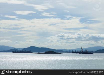 cargo ship Moored offshore. Behind the mountains and the sky is covered with clouds.