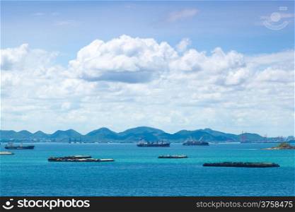 Cargo ships. Moored in the sea near the island. The bright sky in the daytime.