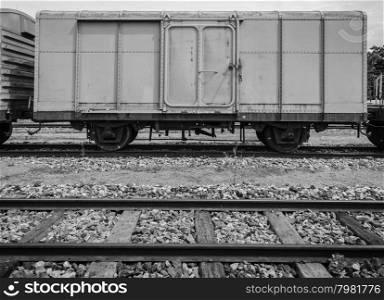 Cargo train and wooden rails track in black and white image