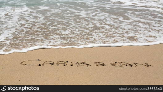 Caribbean words written into sand on beach by sea in St Thomas