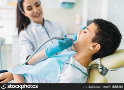 Caries removal procedure, pediatric dentistry, children stomatology. Female dentist drilling teeth, dental clinic. Caries removal procedure, children stomatology