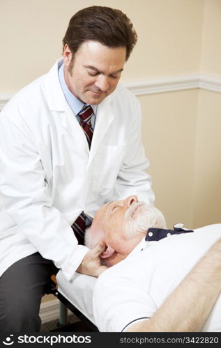 Caring chiropractor adjusts a senior man&rsquo;s neck.