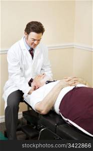 Caring chiropractor gently adjusts a senior man&rsquo;s neck.