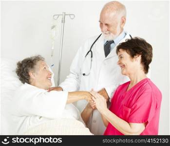 Caring doctor and nurse greeting hospital patient.