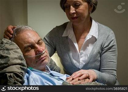 Caring female nurse with sleeping senior male patient