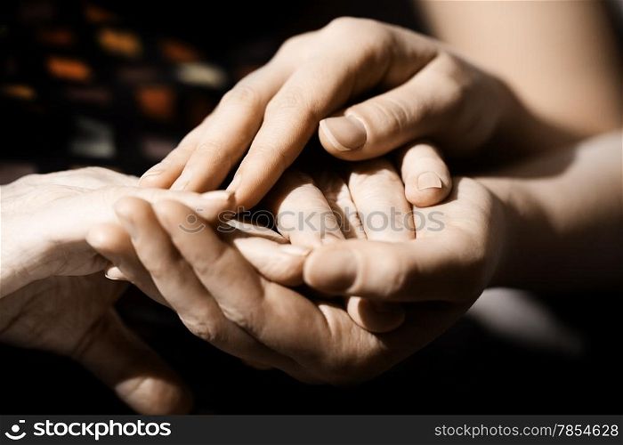 Caring hands of a loving young woman clasping the hands of an elderly person tenderly in her palms