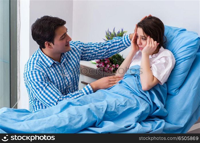 Caring loving husband visiting pregnant wife in hospital