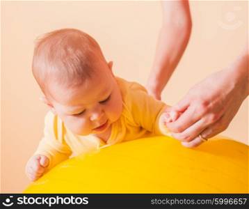 Caring mother doing sport exercises with her baby on fitball. The Baby exercises