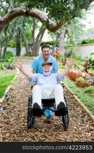 Caring nursing home orderly pops a wheelie with an elderly man&rsquo;s wheelchair. They are having fun.