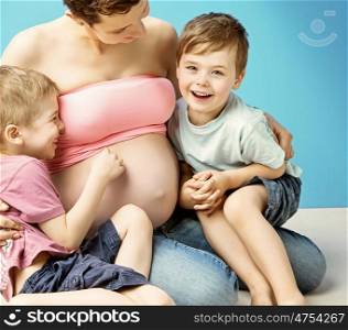 Caring pregnant mother embracing her lovely sons