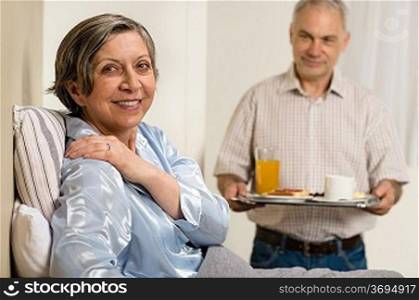 Caring senior man bringing breakfast to her sick wife
