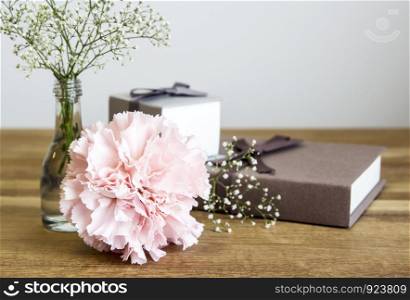 Carnation flower and gift box on wooden table