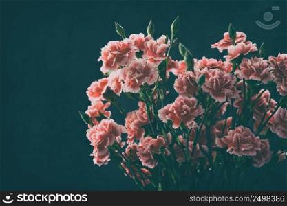 Carnation flowers bouquet vintage color toned over dark moody art background with copy space.