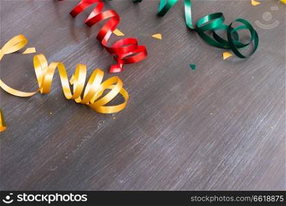 Carnaval festive curling paper with copy space on dark wood. Carnaval decorations on dark wooden background