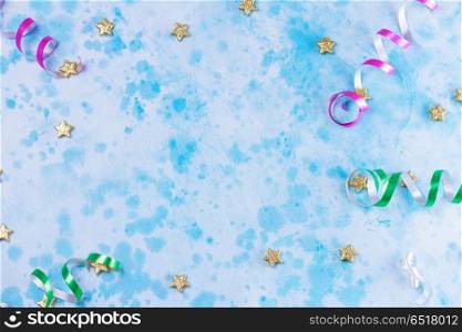 Carnival festive background. Bright colorful carnival or party frame of streamers and confetti on blue table. Flat lay style, birthday or party greeting card with copy space.