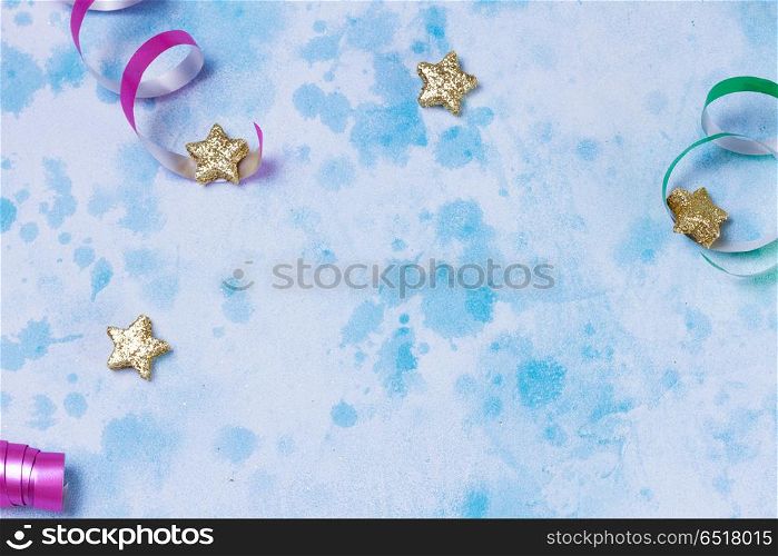 Carnival festive background. Bright colorful carnival or party frame of streamers and confetti on blue table background. Flat lay style, birthday or carnival party greeting card with copy space.