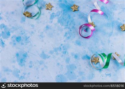 Carnival festive background. Bright colorful carnival or party frame of streamers and confetti on blue table. Flat lay style, birthday or carnival party greeting card with copy space.