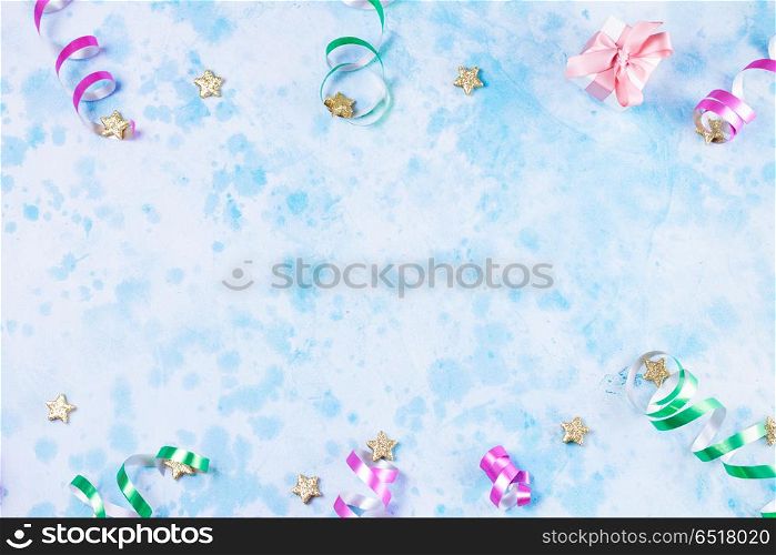 Carnival festive background. Bright colorful carnival or party scene frame of streamers and confetti on blue table. Flat lay style, birthday or party greeting card with copy space.