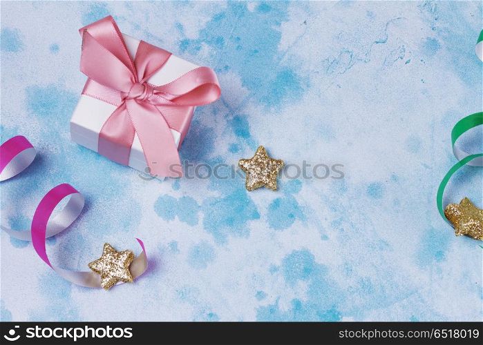 Carnival festive background. Bright colorful carnival or party scene of gift box, streamers and confetti on blue table. Flat lay style, birthday or party greeting card with copy space.