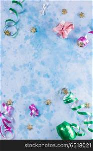 Carnival festive background. Bright colorful carnival or party scene of streamers and confetti on blue table. Flat lay style, birthday or carnival party greeting card with copy space.