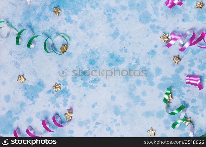 Carnival festive background. Bright colorful carnival or party scene of streamers and confetti on blue table. Flat lay style, birthday or party greeting card with copy space.