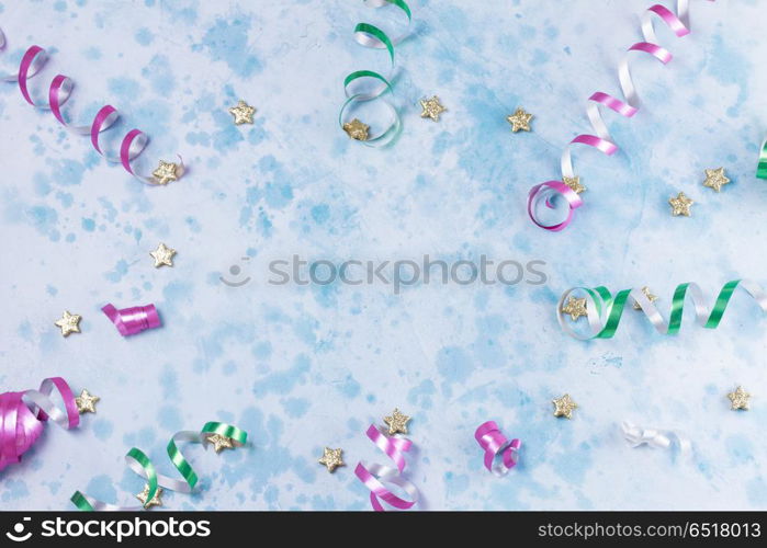 Carnival festive background. colorful carnival or party frame of streamers and confetti on blue table. Flat lay style, birthday or party greeting card with copy space.