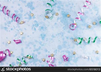 Carnival festive background. colorful carnival or party frame of streamers and confetti on blue table. Flat lay style, birthday or party greeting card with copy space.
