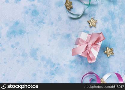 Carnival festive background. colorful carnival or party scene of gift box, streamers and confetti on blue table. Flat lay style, birthday or party greeting card with copy space.