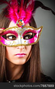 Carnival night life. Attractive woman face with mysterious mask on grey background in studio.