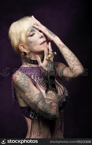 carnival portrait of adult girl with many tattoos on her skin, decorated glitter bra and bizarre accessories