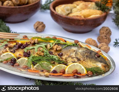 carp with lemon, walnuts and raisins on the plate