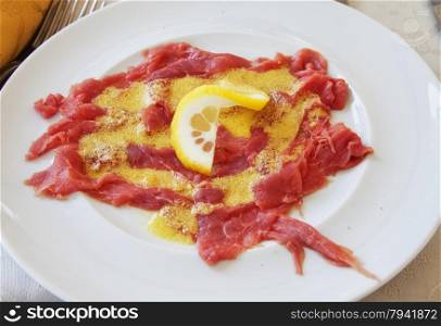 Carpaccio of raw meat with egg over white plate, horizontal image