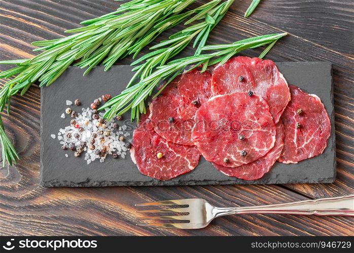 Carpaccio - slices of raw beef on the stone board