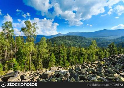 Carpathian Mountain (Ukraine) summer landscape with sky and cumulus clouds, fir forest and slide-rocks.